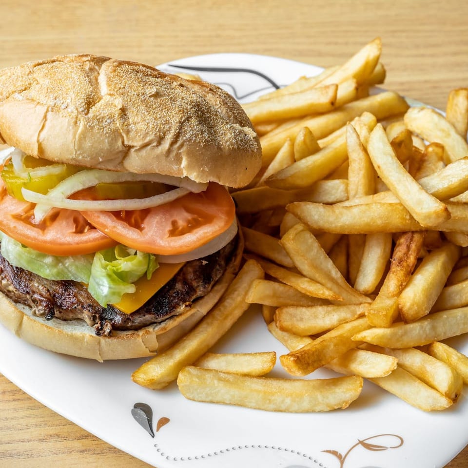 A Big John's Pizza & Pasta cheeseburger with lettuce, tomato, onion, and pickles, served with fries.
